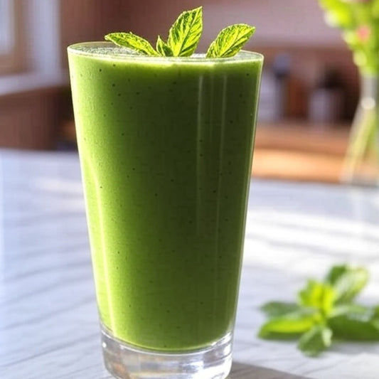 Green smoothie in a glass with mint leaves on a wooden table